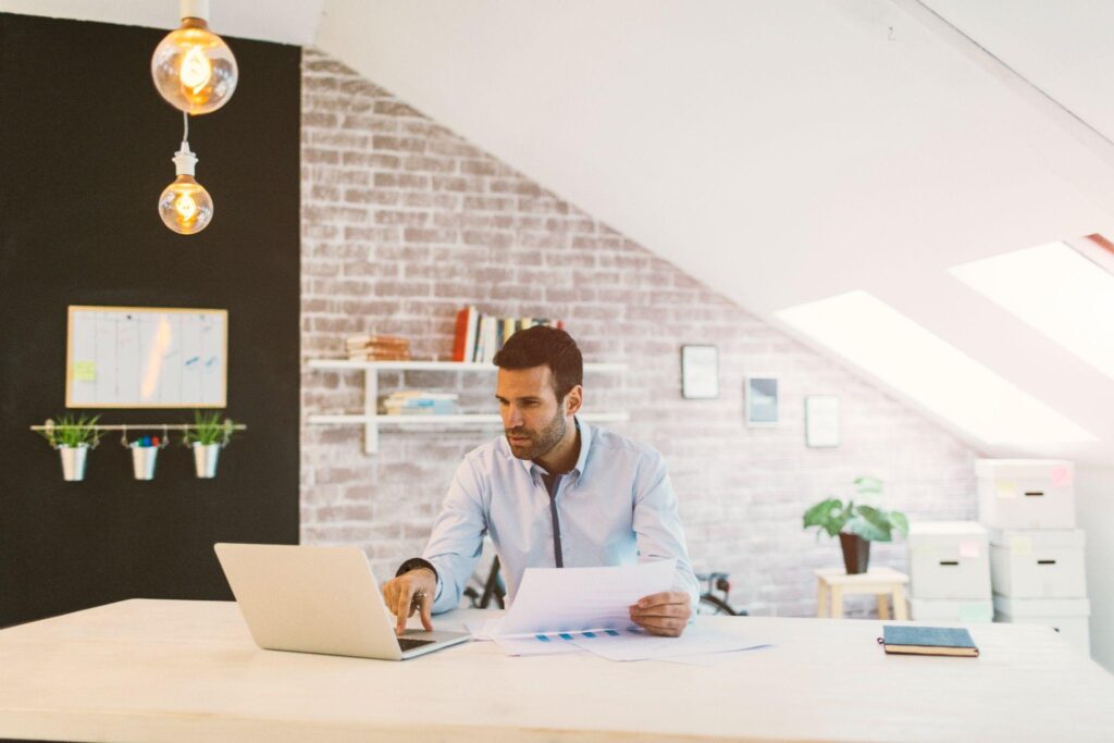 Agenturinhaberin oder Agenturinhaber in moderner AXA Agentur am Laptop mit betriebswirtschaftlicher Auswertung
